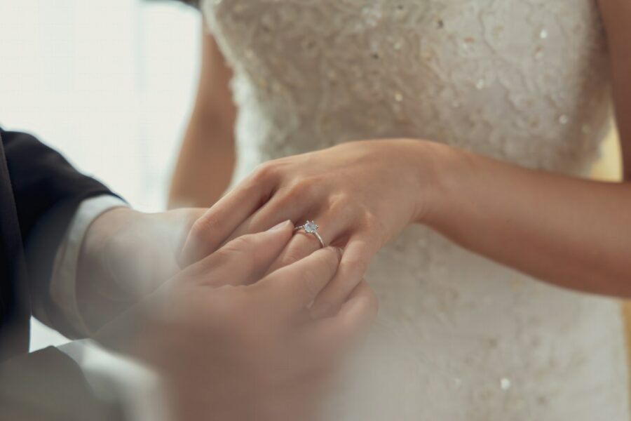 A groom places a wedding ring on his bride's finger during their wedding ceremony.